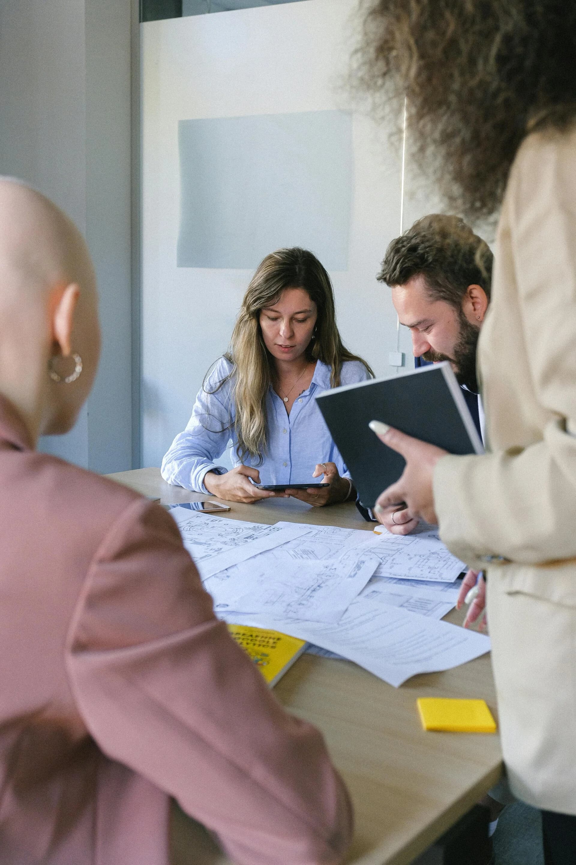 Medewerkers van GNRL Works bespreken tekeningen en planning aan een werktafel